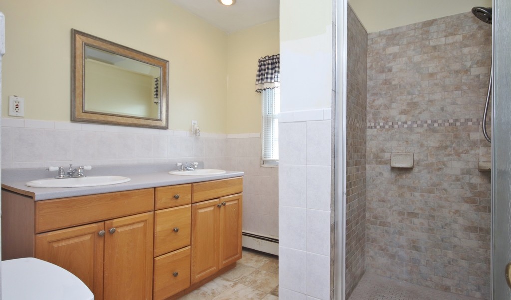 Bathroom has double sinks and stall shower